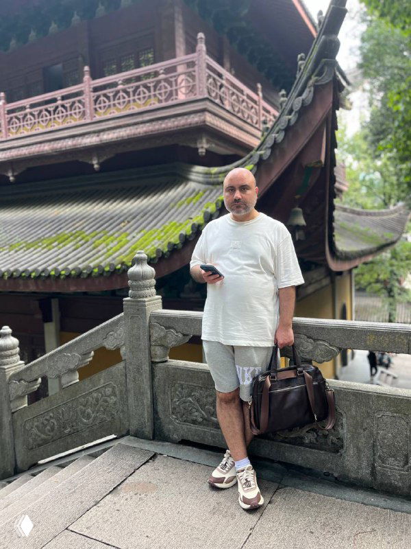 Полноростовое фото автора в светлой одежде на каменном мостике у традиционного строения, демонстрирующее внешний вид до/после похудения.