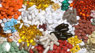 Разноцветные таблетки и капсулы на белом фоне; иллюстрация приёма лекарств до, во время или после еды.