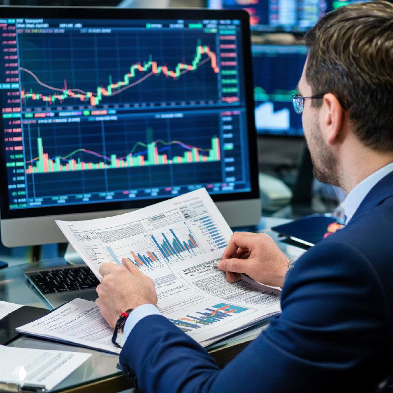 Человек в офисе перед монитором с финансовыми графиками и диаграммами, держащий печатную страницу с отчётом — иллюстрация анализа рынка и NFP.