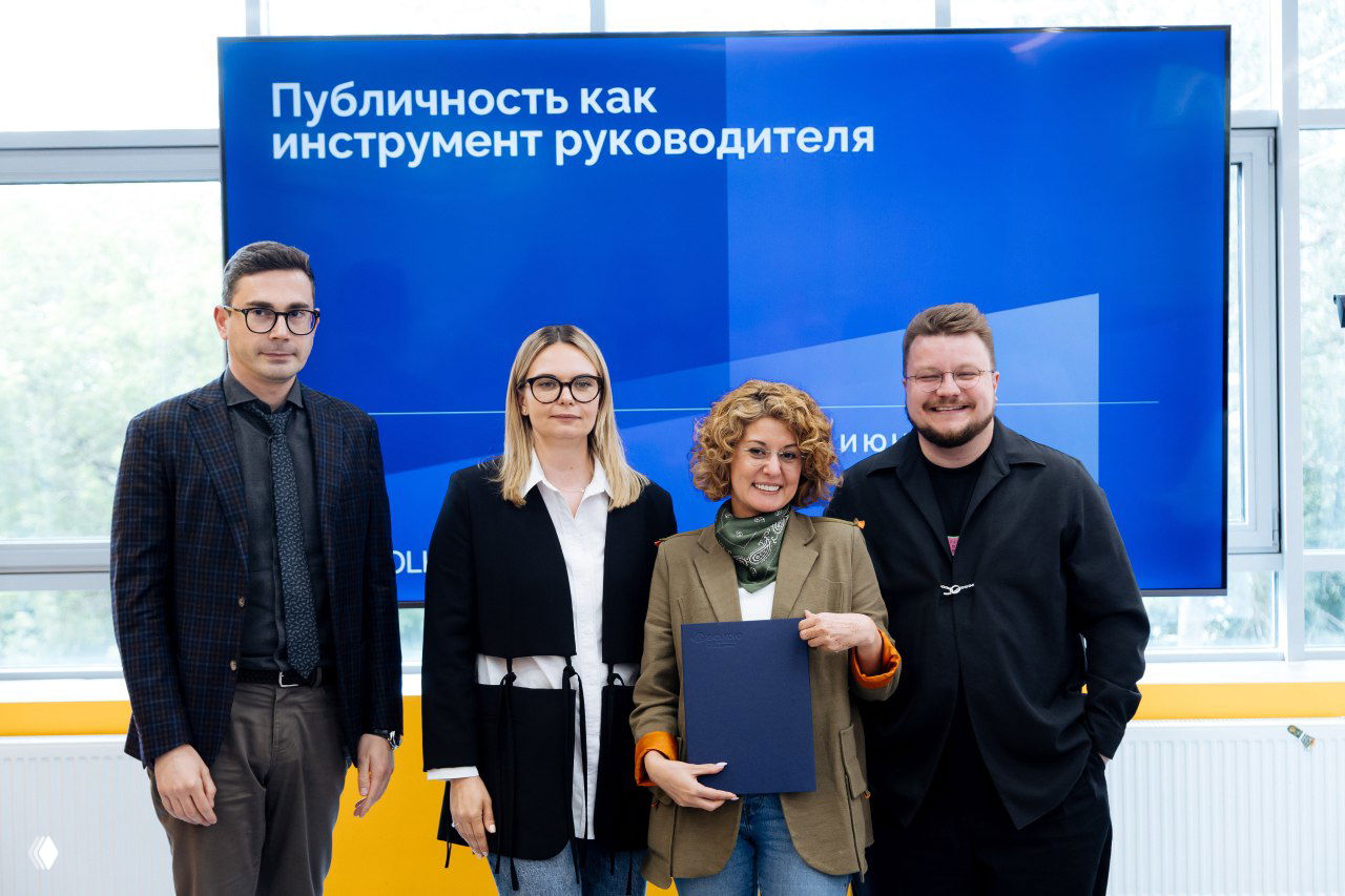 Групповая фотография выпускников программы на фоне экрана с надписью «Публичность как инструмент руководителя», вручение сертификата Ангелине.