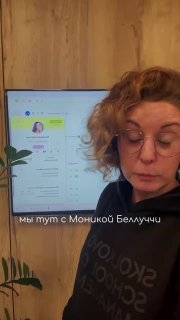Крупный план сотрудницы на фоне экрана с интерфейсом Sonata — кадр во время тестирования и демонстрации возможностей PMS в офисе.