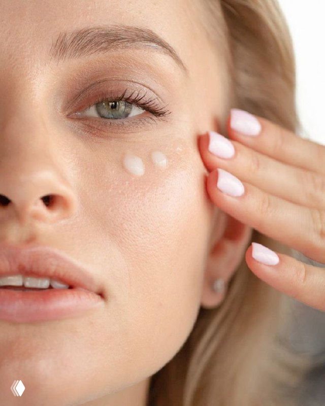 Крупный план: женщина наносит крем под глаз; видна тонкая и нежная кожа вокруг глаза с акцентом на уход и гидратацию.