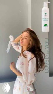 Женщина с длинными гладкими волосами на светлом фоне; в кадре флакон крем‑маски Loved by You, демонстрирующий блеск и уход.