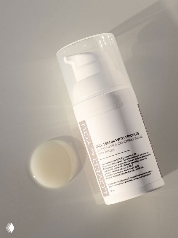 Фото крупным планом белого диспенсерного флакона-сыворотки Loved by You на светлом фоне; видна часть этикетки и крышки.