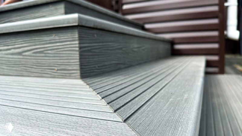 Макрофото угловой облицовки из композитной террасной доски: ступень и торец, видно рельефную структуру и аккуратный стык покрытий на крыльце.