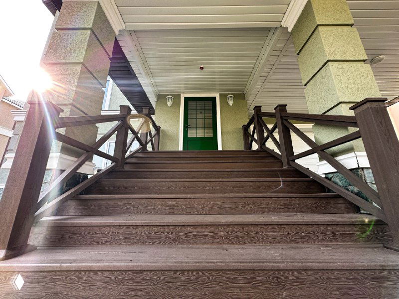 Крыльцо с лестницей, облицованное ДПК: вид ступеней, перил и входной зоны, демонстрация внешнего использования композитной террасной доски на частном доме.