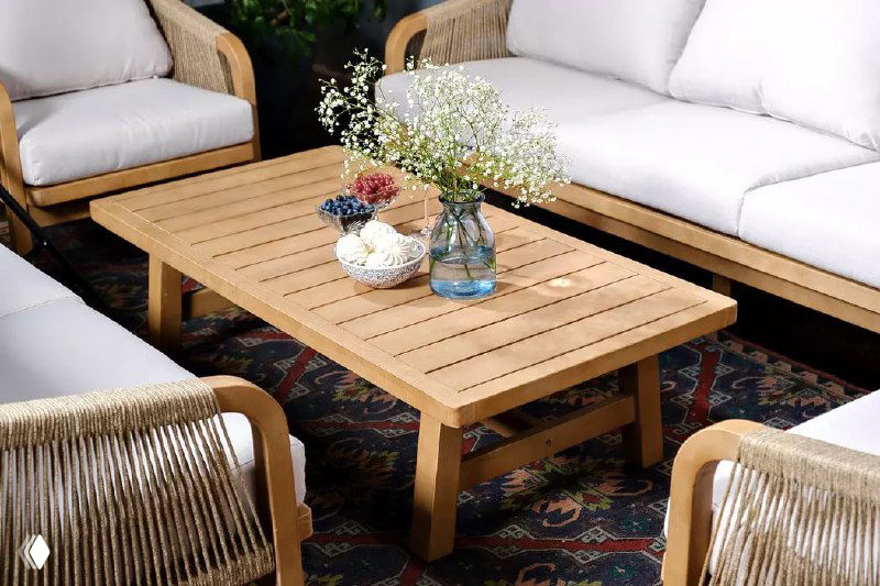 Низкий журнальный столик из светлого дерева в окружении плетёных диванов TALARA; на столе вазы и декоративные элементы, натуральный стиль.
