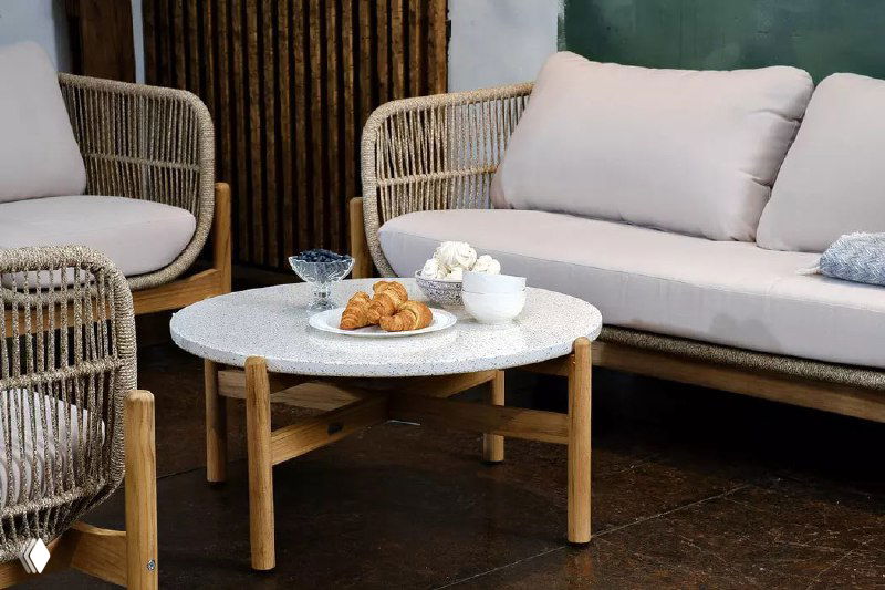 Низкий круглый стол и диван TALARA в пастельных тонах: гармоничное сочетание плетёных фасадов, подушек и деревянных ножек в интерьере.