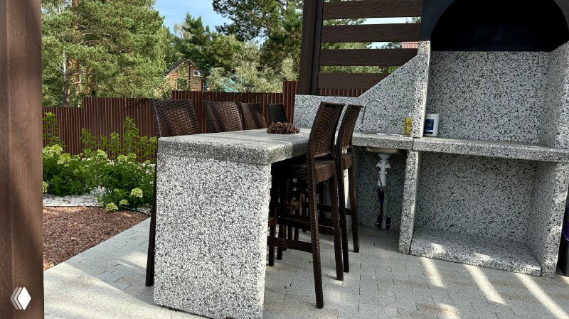 Барная стойка и барные пластиковые стулья у уличного камина/мангала на террасе, сочетание фактур и практичных материалов для дачи.