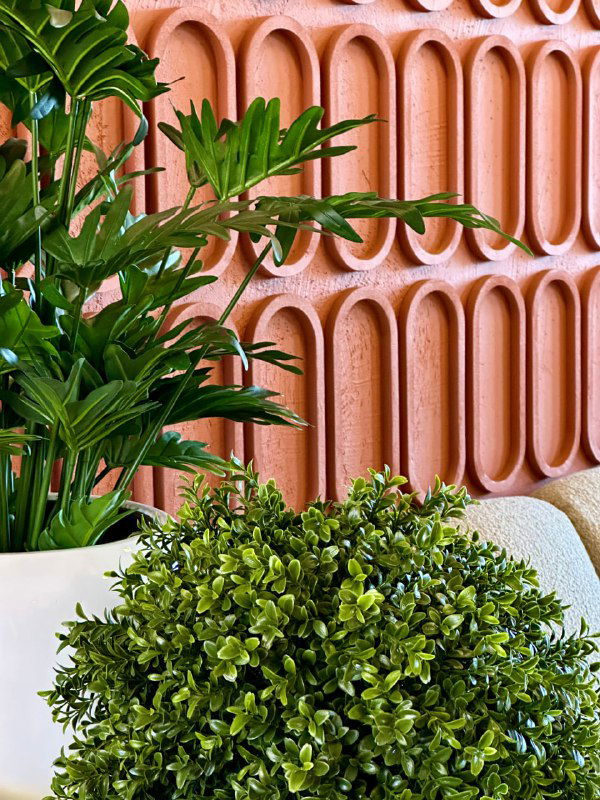 Низкий план зелёных искусственных кустов и декоративных растений на столе и возле стены внутри ресторана «Твиани», акцент на листьях.