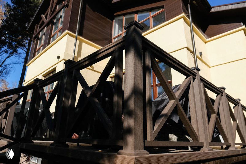 Деталь балюстрады и угол крыльца на террасе из ДПК под разными углами, тени и древесная фактура на переднем плане.