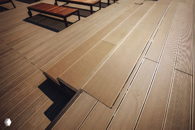 Крупный план террасной доски из ДПК: рифленая поверхность, стыки панелей и текстура композитного материала крупным планом.