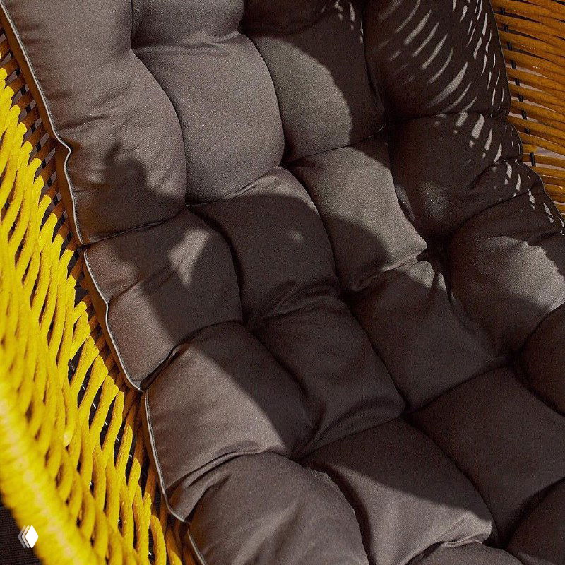 Крупный план тёмно‑серой стёганой подушки внутри кресла‑кокона, видна текстура ткани и плотность наполнителя.