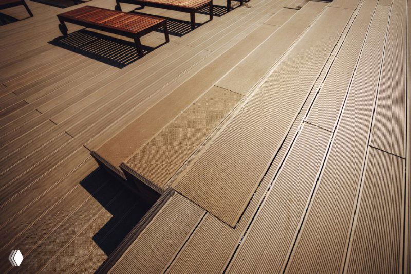 Крупный план монтажа террасной доски NewWood: профилированные рейки, стыки настила и фактура поверхности в деталях.