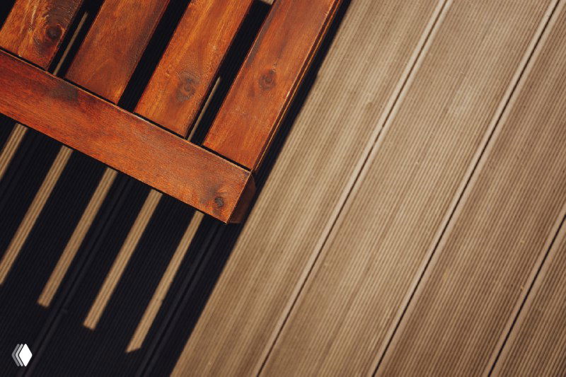 Макросъёмка текстуры террасной доски NewWood рядом с деревянной поверхностью лежака: поперечный рельеф и древесный оттенок.