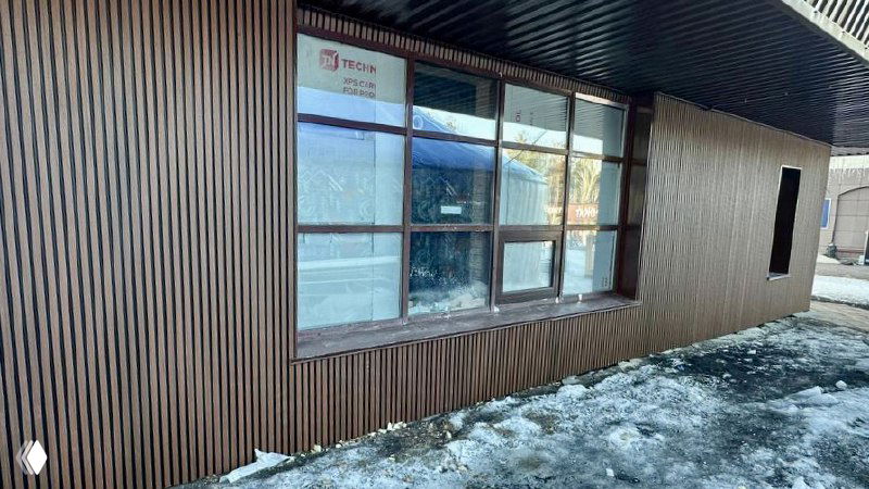 Фрагмент фасада с окном и ламелями из ДПК; видно отражение в стекле, соединение панелей с карнизом и общий стиль отделки.