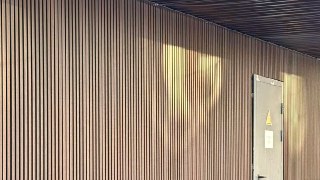 Детальный кадр вертикальных брусковых панелей из ДПК — коричневый оттенок, текстура, монтажные швы и ровная поверхности облицовки на фасаде.