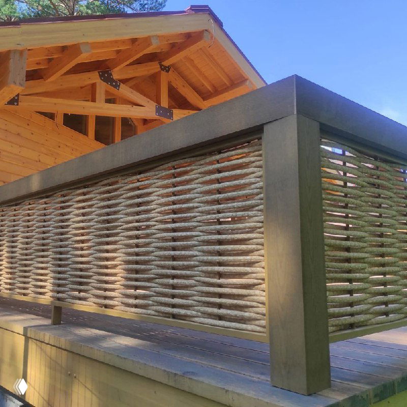 Ограждение из полимерной лозы между террасой и территорией участка: ровное горизонтальное плетение и контраст тёплой древесины рамы.