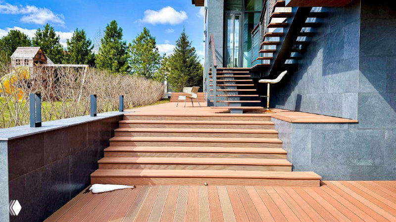 Широкие ступени из ДПК ведут к балкону; аккуратный монтаж и аккуратные стыки между досками, вид со стороны сада.