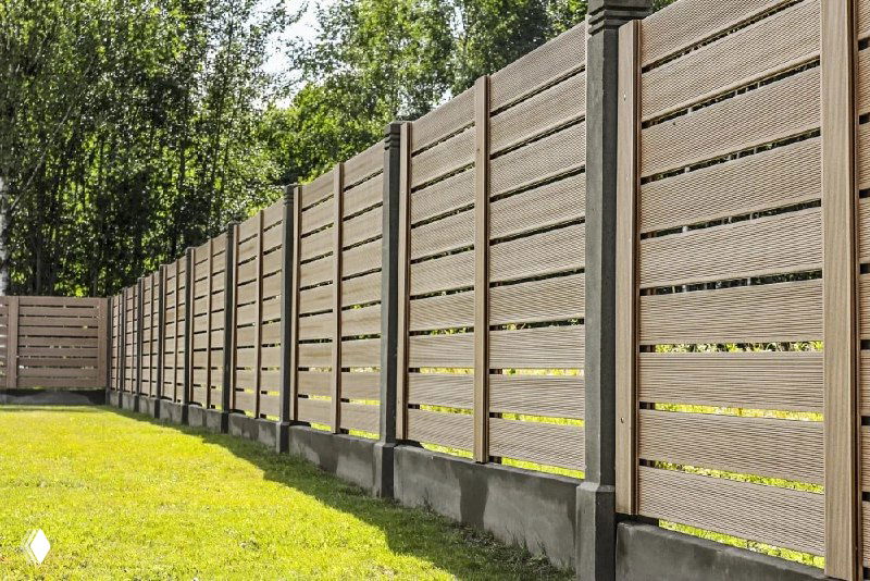 Современный светлый забор из горизонтальных реек на невысоком основании, визуально расширяющий пространство и придающий аккуратный вид участку.