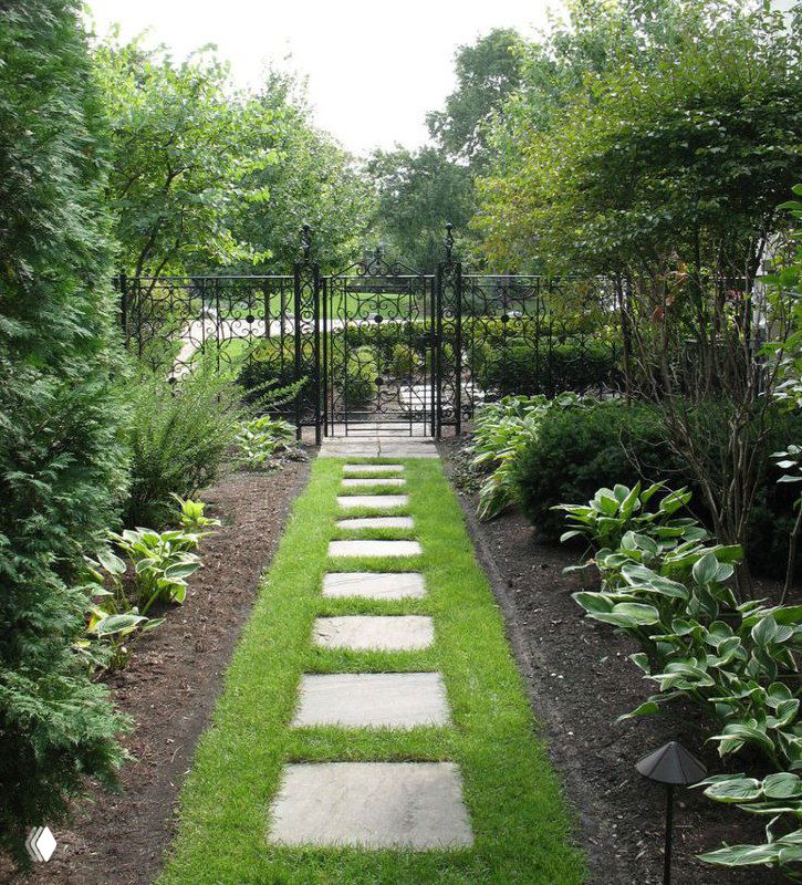 Узелок тропинки с квадратными плитами и узкой зелёной дорожкой из рулонного газона между кустарниками — уютный садовый проход