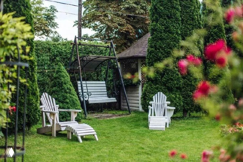 Зона отдыха на рулонном газоне с креслами-лежаками и качелями в саду — пространство для релакса и вечеринок на свежем воздухе