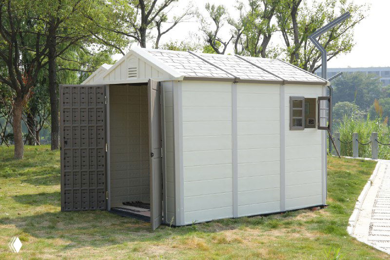 Пластиковый двухсекционный хозблок с открытой дверью, показано внутреннее пространство и входная зона для хранения садового инвентаря.