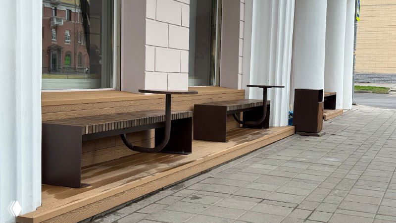 Крупный план деревянных скамеек и столиков на настиле из террасной доски Polivan; видно рельеф поверхности и металлические опоры мебели.
