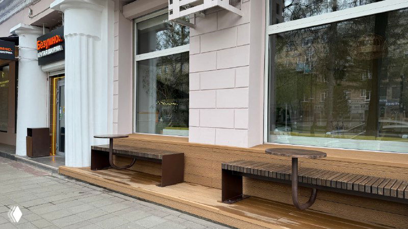 Перспективное фото части террасы Port Coffee с одной из скамеек на настиле Polivan, видна структура доски и городской фон за пределами площадки.