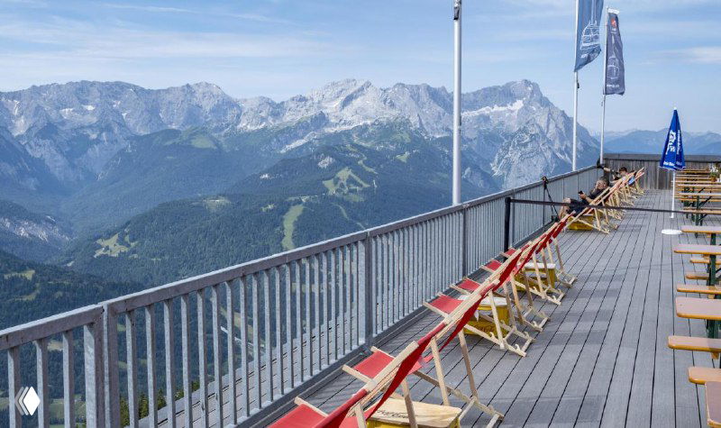 Длинная смотровая площадка или терраса в горах с шезлонгами и ограждением — пример открытого настила, выдерживающего пешеходную нагрузку и погодные условия.