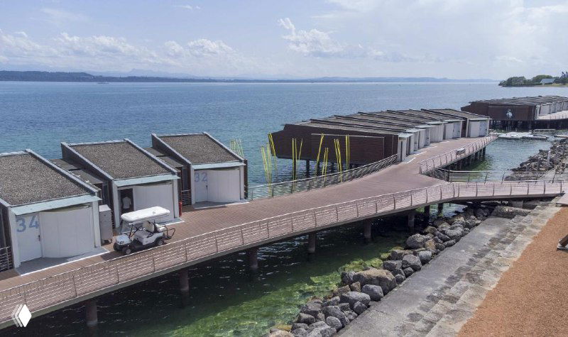 Набережная с домиками и променадом над водой — пример использования прочного настила из ДПК в прибрежных зонах и курортной инфраструктуре.