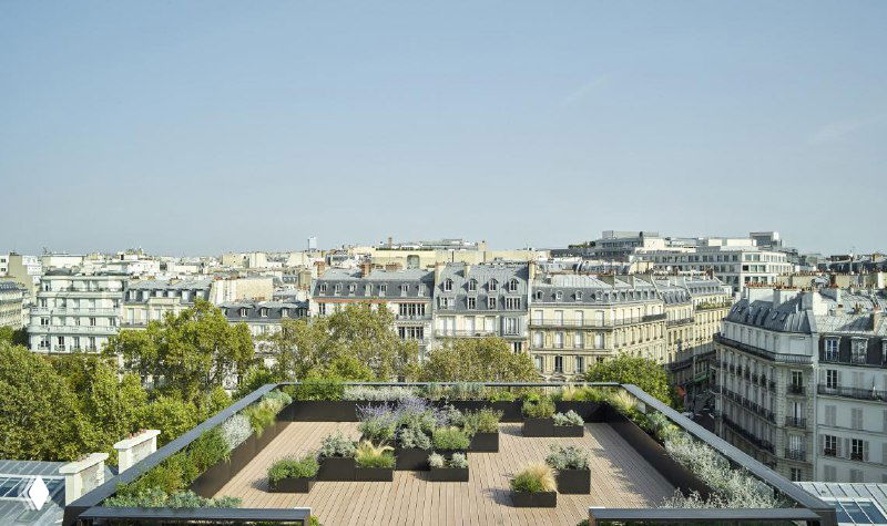 Панорамный вид на городской пейзаж с зелёной террасой на крыше многоквартирного дома — пример применения настила для создания зоны отдыха в черте города.