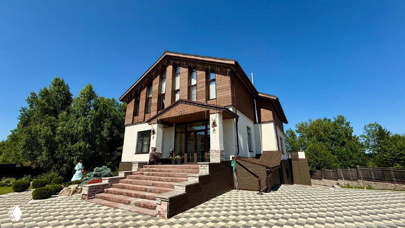 Вид со стороны входной группы: крыльцо и ступени рядом с облицованным фасадом, аккуратная укладка материалов и ландшафт вокруг дома