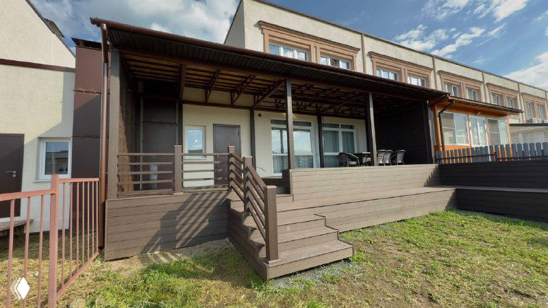 Угол террасы и лестница: коричневые доски ДПК, перила и ступени, вид сбоку показывающий переход от дома к участку и рабочую планировку.