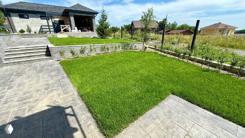 Рулонный газон на приусадебном участке: ровная зелёная поверхность вблизи патио, подходящая для игр, пикников и отдыха босиком.