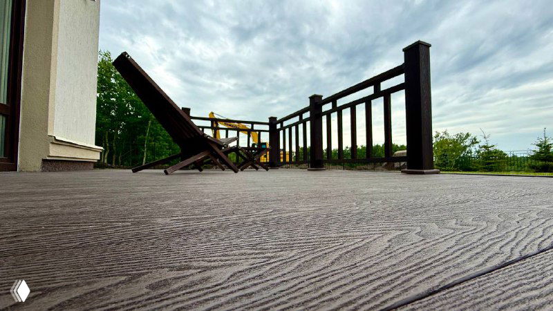 Широкий ракурс низкого угла на настил и ограждение террасы из ДПК Polivan SINGARAJA коричневого оттенка — подчёркнута фактура доски и ровная поверхность.