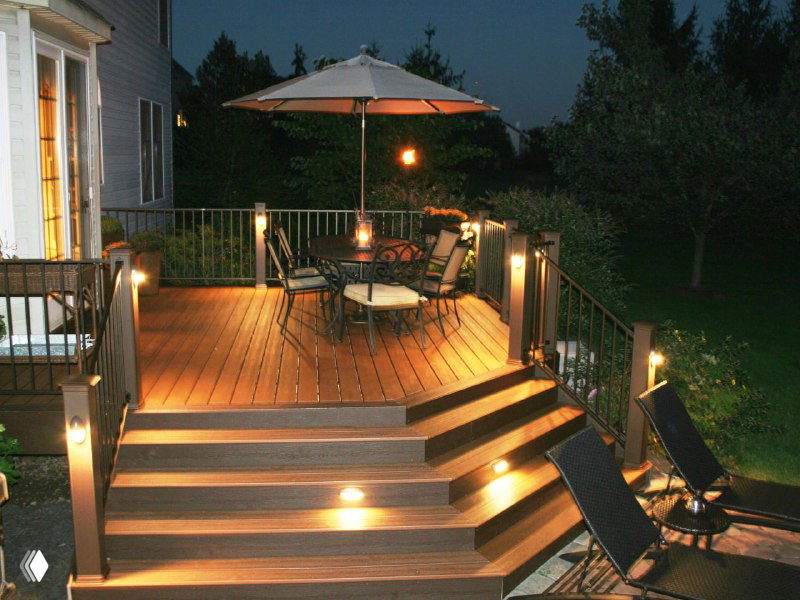 Вечерняя терраса с подсветкой в ступенях и полу: тёплое освещение у столовой зоны и лежаков.
