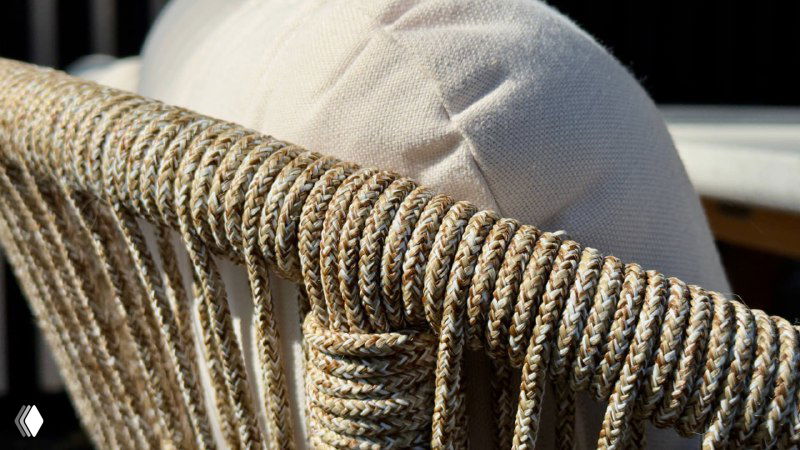 Крупный план плетёного кресла из коллекции TALARA — фактура верёвочной спинки и мягкая подушка на фоне террасного настила