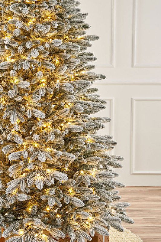 Крупный план ветвей заснеженной версии Самарской ели с подсвеченными лампочками, текстура искусственного снега и равномерность покрытия.