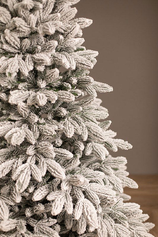 Крупный план ветвей заснеженной ели, демонстрирующий текстуру искусственного снега и плотность иголок для оценки качества и внешнего вида товара.