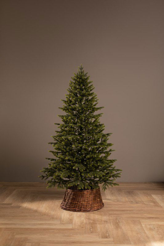 Фотография целой искусственной ёлки «Люблинская» в корзинном основании на деревянном полу, чётко видна форма и густота ветвей.