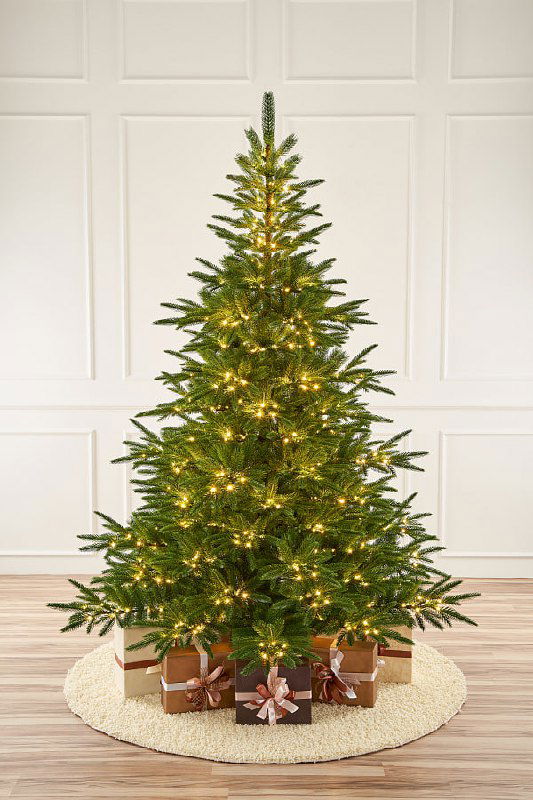 Фронтальный кадр литой премиум‑ёлки «Пальмира» в интерьере: ровная форма, густая хвоя и равномерное распределение тёплых огоньков встроенной гирлянды.