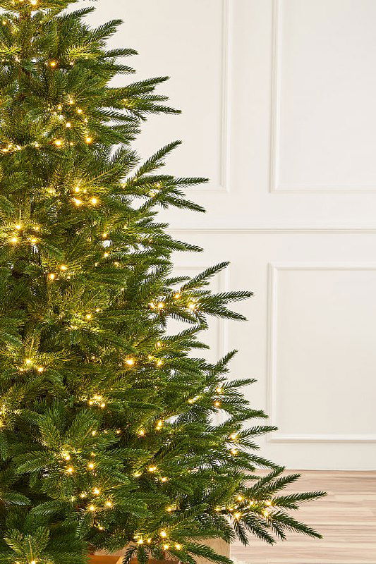 Боковой ракурс литой ёлки «Пальмира»: видна глубина ветвей, равномерность распределения иголок и мягкое сияние встроенной гирляндной подсветки.