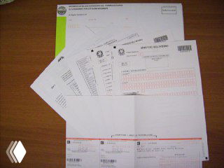 Фото: бело‑жёлтый комплект КИТ и распечатанные документы на столе — пример пакета документов, который подаётся для продления пермессо в Италии