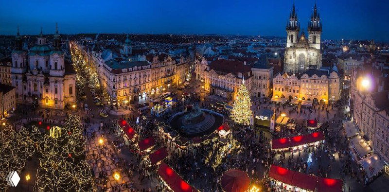 Панорамный ночной вид на европейскую площадь с праздничными огнями, рождественскими киосками и силуэтами церковных шпилей — иллюстрация к теме поездок и ВНЖ.