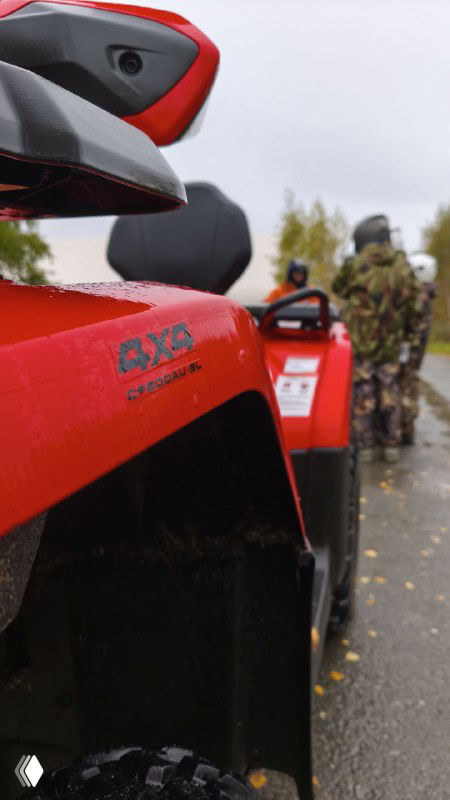 Детальный кадр красного квадроцикла в строю; видно маркировку на пластике и участников, готовящихся к старту в колонне машин.