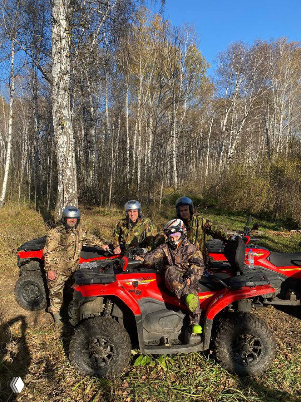 Трое людей на квадроциклах на лесной тропе среди высоких берёз, осенняя атмосфера и ровная дорога, участники в шлемах и камуфляже.