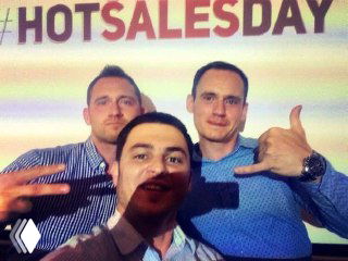 Групповое фото с участниками мероприятия: трое мужчин улыбаются и жестами подчеркивают хорошую атмосферу, на заднем плане брендовый фон HOTSALESDAY.