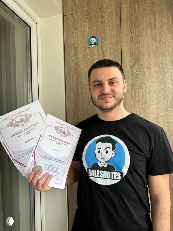 Автор держит свидетельства о регистрации товарных знаков и позирует в футболке с логотипом Salesnotes.