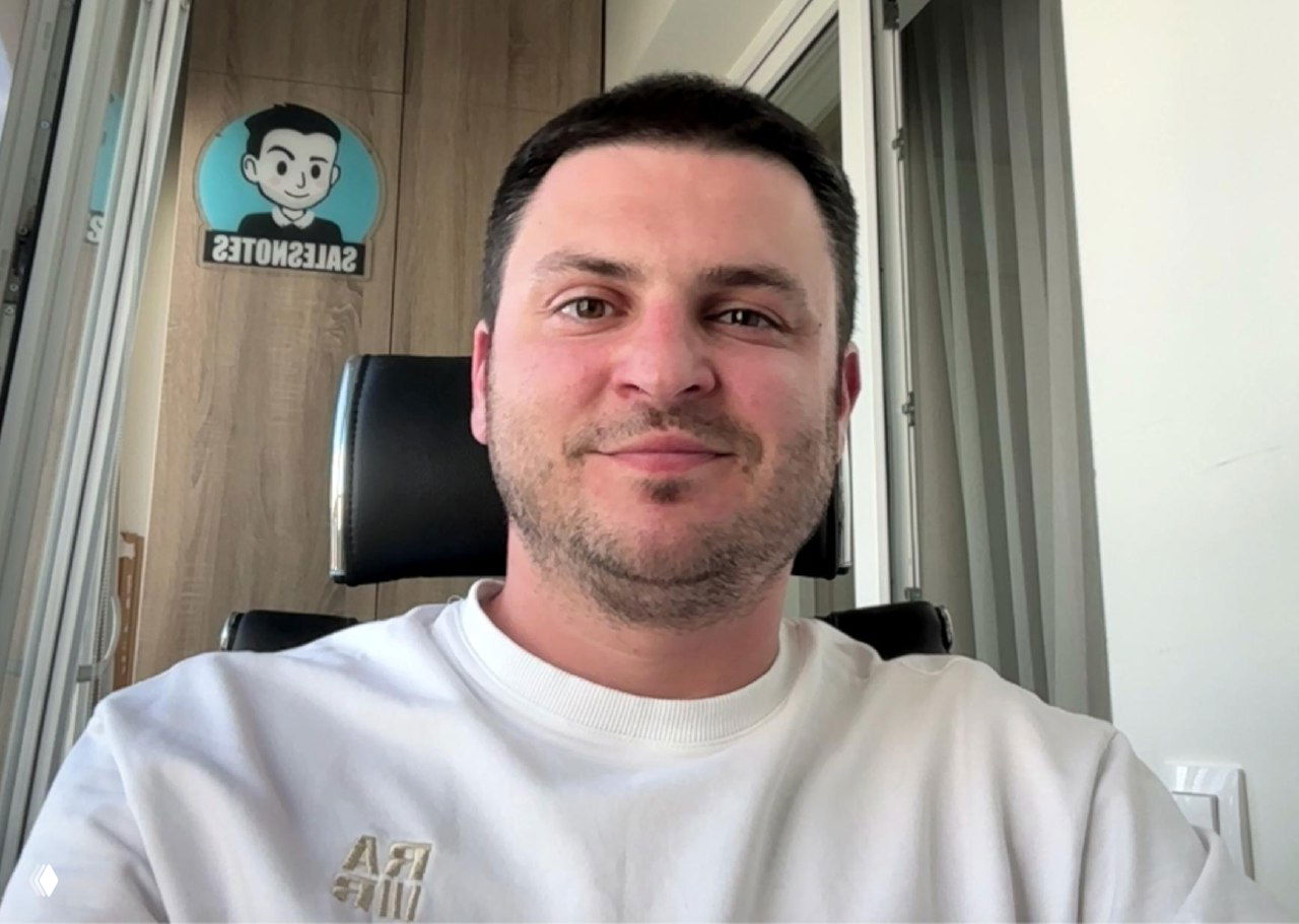 Автор в офисе: портрет на фоне шкафа с декоративной вывеской и логотипом Salesnotes; видны кресло и часть рабочего интерьера.